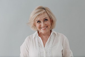 Portrait of smiling senior woman against gray background