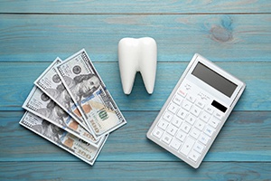 Tooth, calculator, and money on tabletop