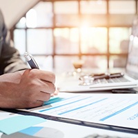 Person filling out insurance form on clipboard