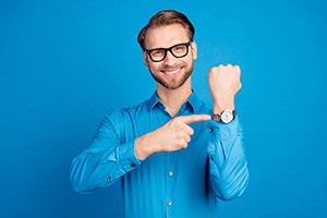 Smiling man pointing at his wristwatch