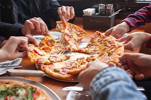 Friends reaching for slices of pizza