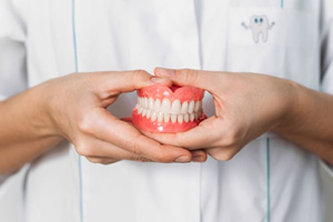 Dental team member holding full set of dentures