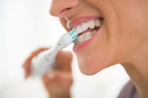 Close-up of woman’s teeth as she uses an electric toothbrush