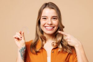 Woman pointing at her teeth while wearing Invisalign aligner