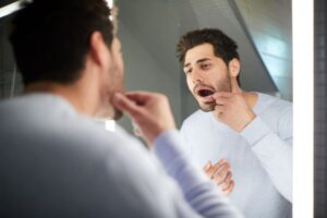 Concerned man examining his mouth in mirror