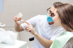 Dentist using model to explain dental implants to patient